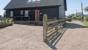 A black building with a tiled roof, a wooden door, and a small window. - 4 bedroom accommodation in Horning, near Norwich (Horning, near Norwich)