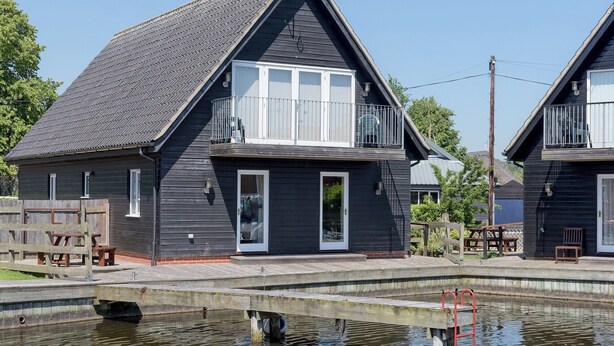 A two-story house with a balcony, a small deck, and a swimming pool. - 4 bedroom accommodation in Horning, near Norwich (Horning, near Norwich)