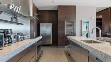 A modern kitchen with stainless steel appliances, a marble countertop, and wooden cabinetry.