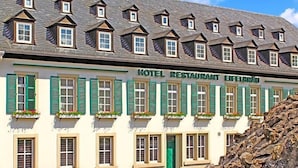 A hotel with multiple windows, green shutters, and a sign reading 'HOTEL RESTAURANT EIFEBERAU.' - Eifelbräu (Bitburg)