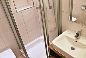 A bathroom with a shower, a sink, and a mirror. - Eifelbräu (Bitburg)
