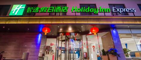 A Holiday Inn Express hotel entrance with a glass revolving door and illuminated signage.