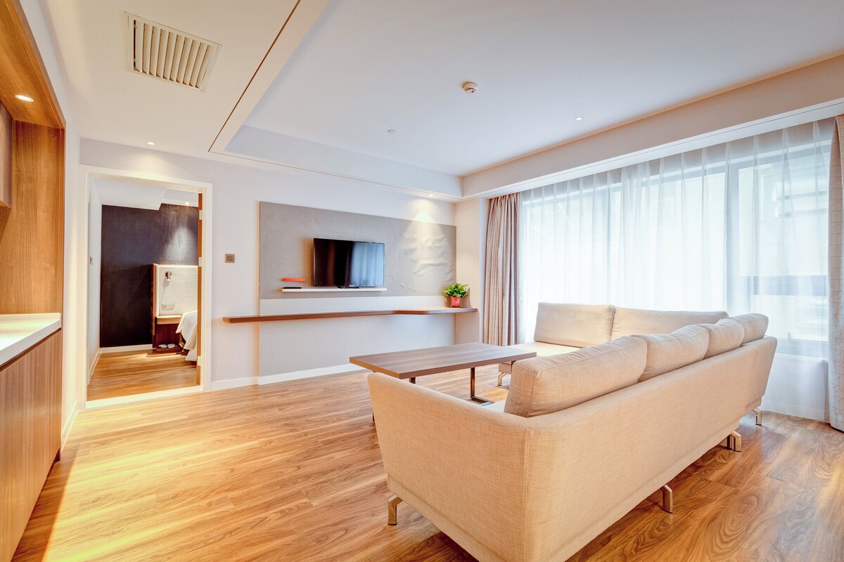 Ein modernes Wohnzimmer mit einer Couch, einem Holztisch und einem an der Wand montierten Fernseher.