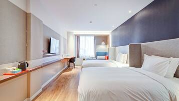 A hotel room with a bed, a desk, a chair, a TV, and a window.