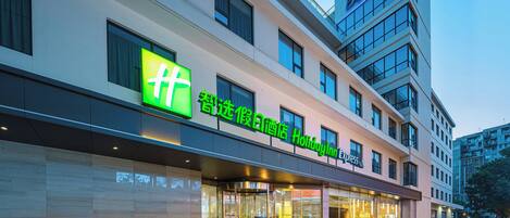 Un hotel Holiday Inn Express con un logotipo verde llamativo, ventanas amplias y una fachada moderna.
