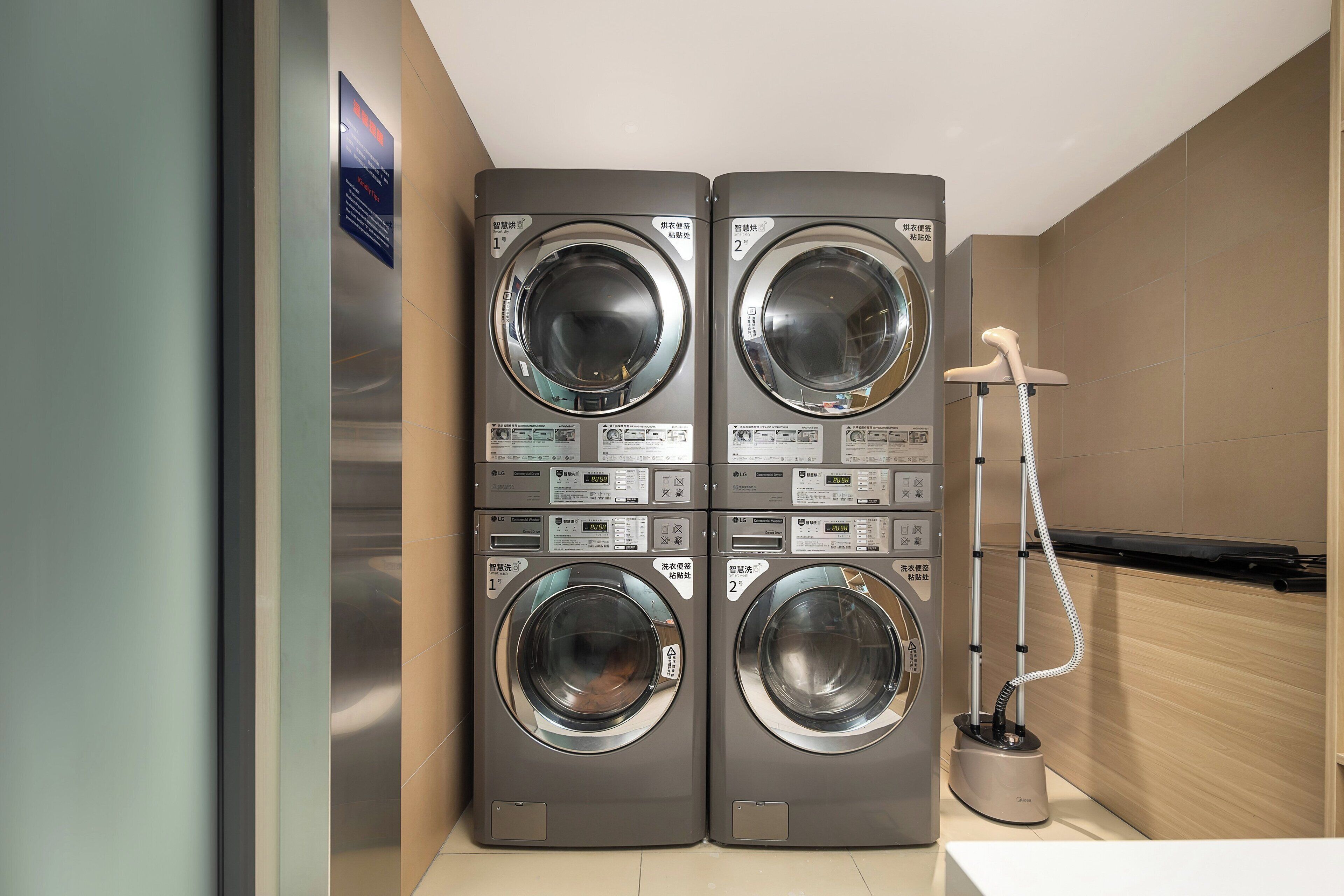 A laundry area with two stacked front-loading washing machines and a hose for water.