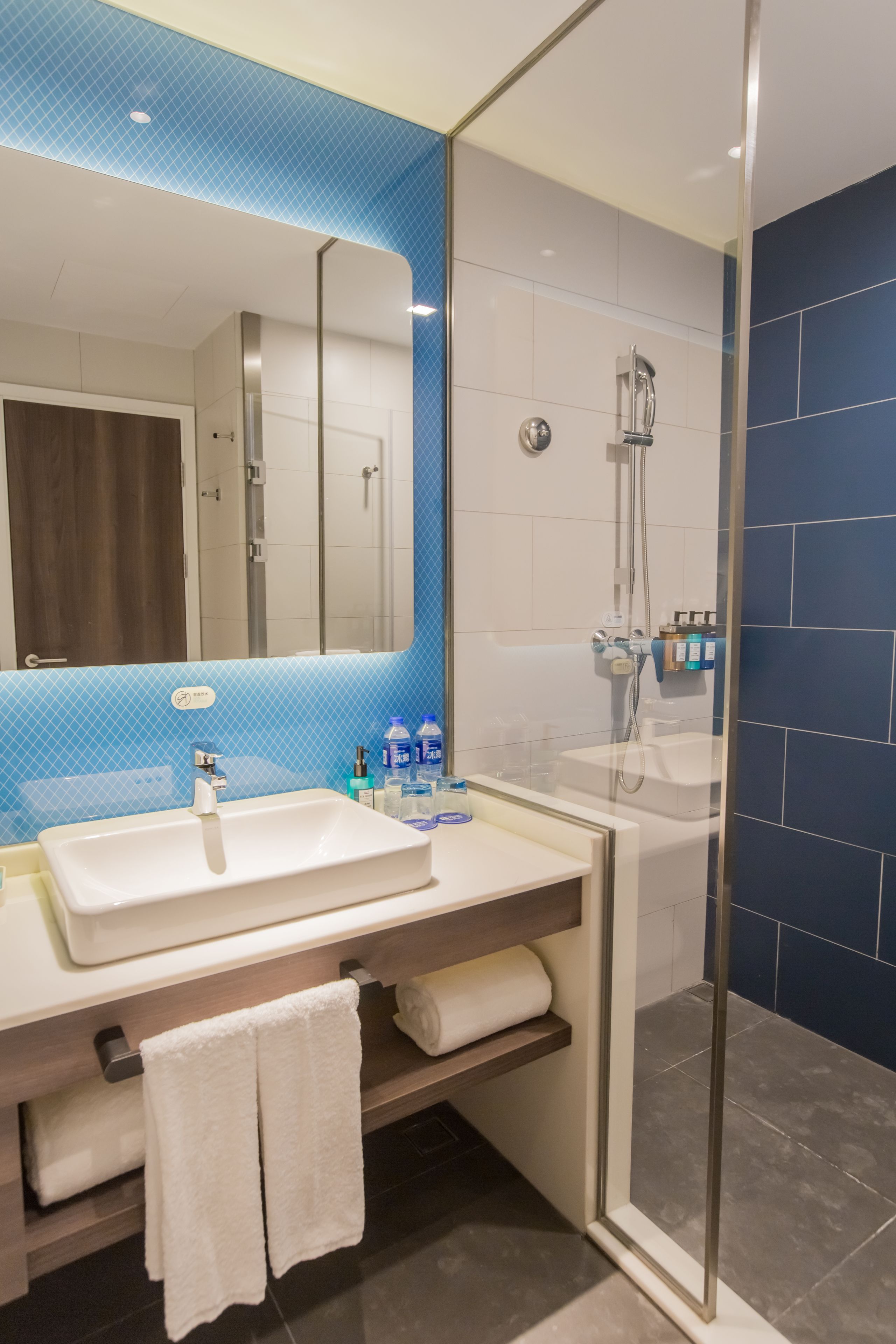 A modern bathroom with a glass shower enclosure, a white sink, and a mirror above the sink.