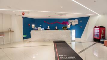 A modern reception area with a blue accent wall, a reception desk, a red telephone, and a digital information board.