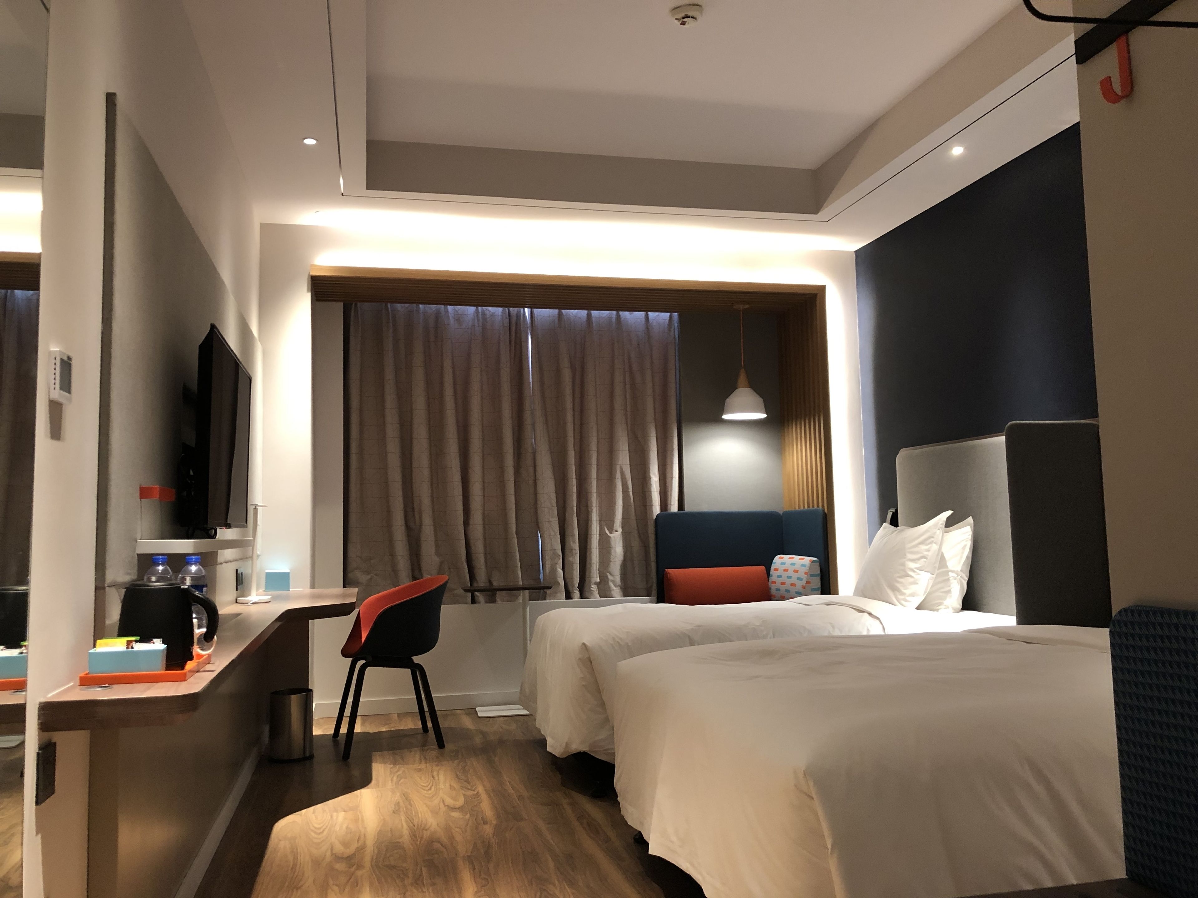 Une chambre d’hôtel moderne équipée de deux lits, d’un bureau, d’une chaise et d’un téléviseur.