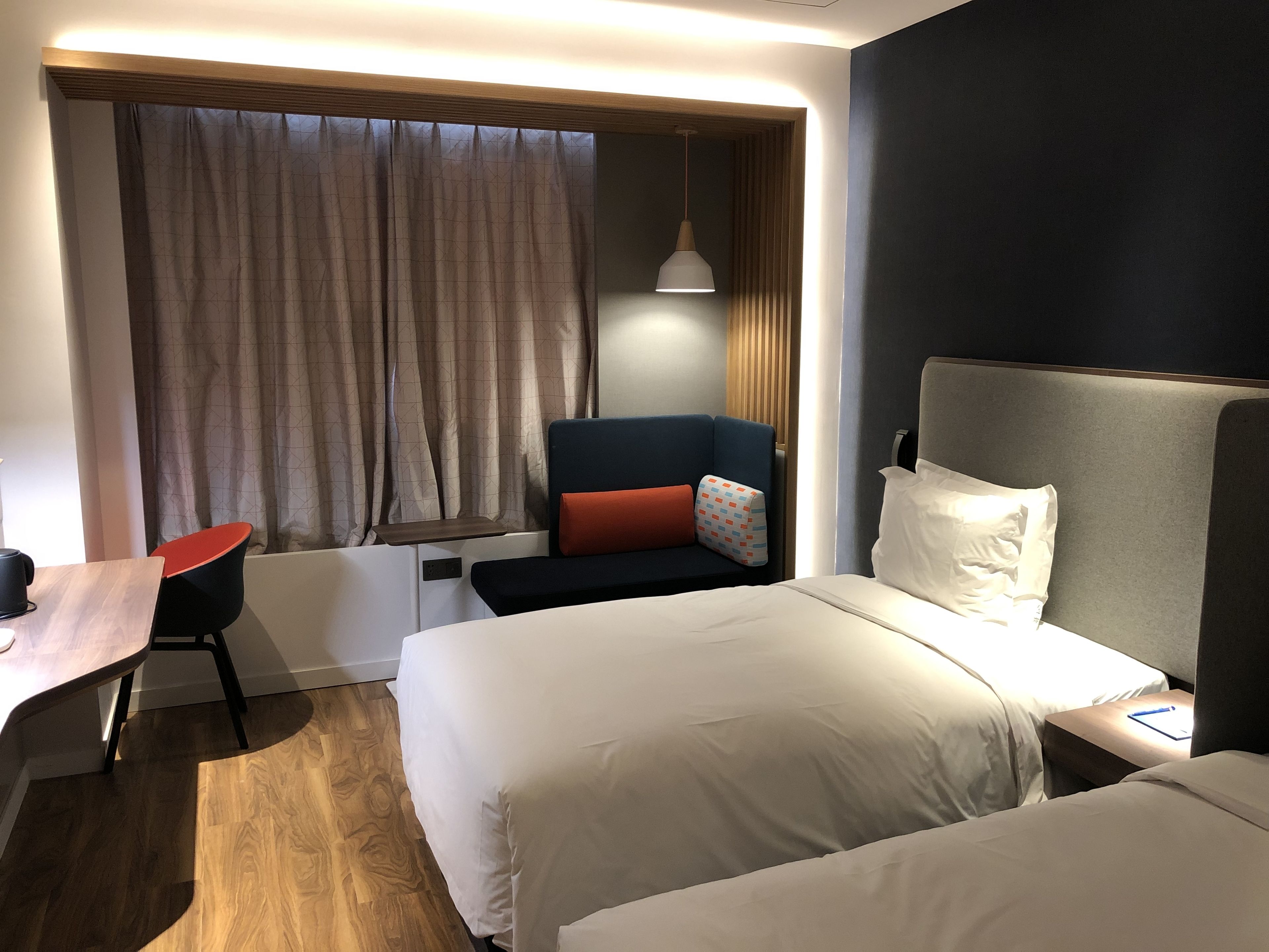 Ein Hotelzimmer mit Bett, Schreibtisch, Stuhl und einem fensterbepflanzten Fenster.