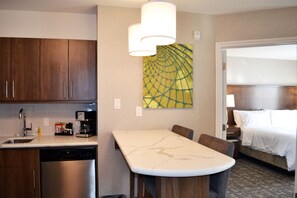 A hotel room with a kitchen area, a dining table, and a bed. - Staybridge Suites Red Deer North  by IHG (Red Deer)
