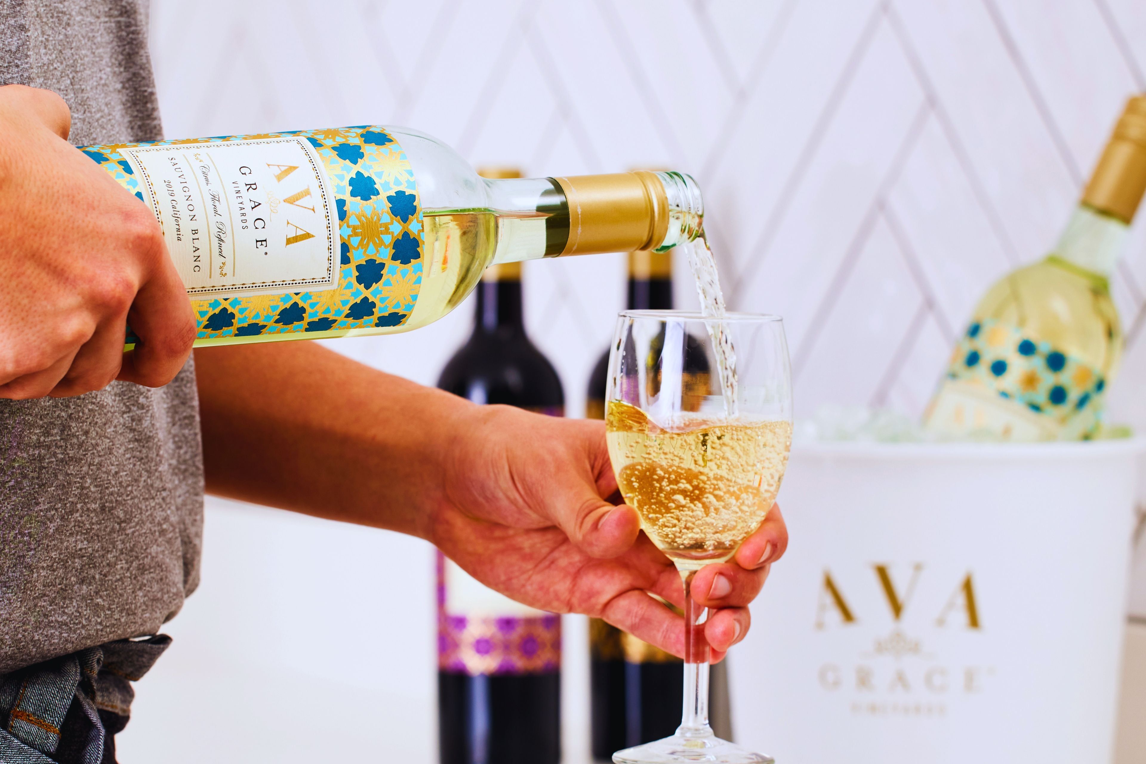 A person pouring a bottle of white wine into a glass.