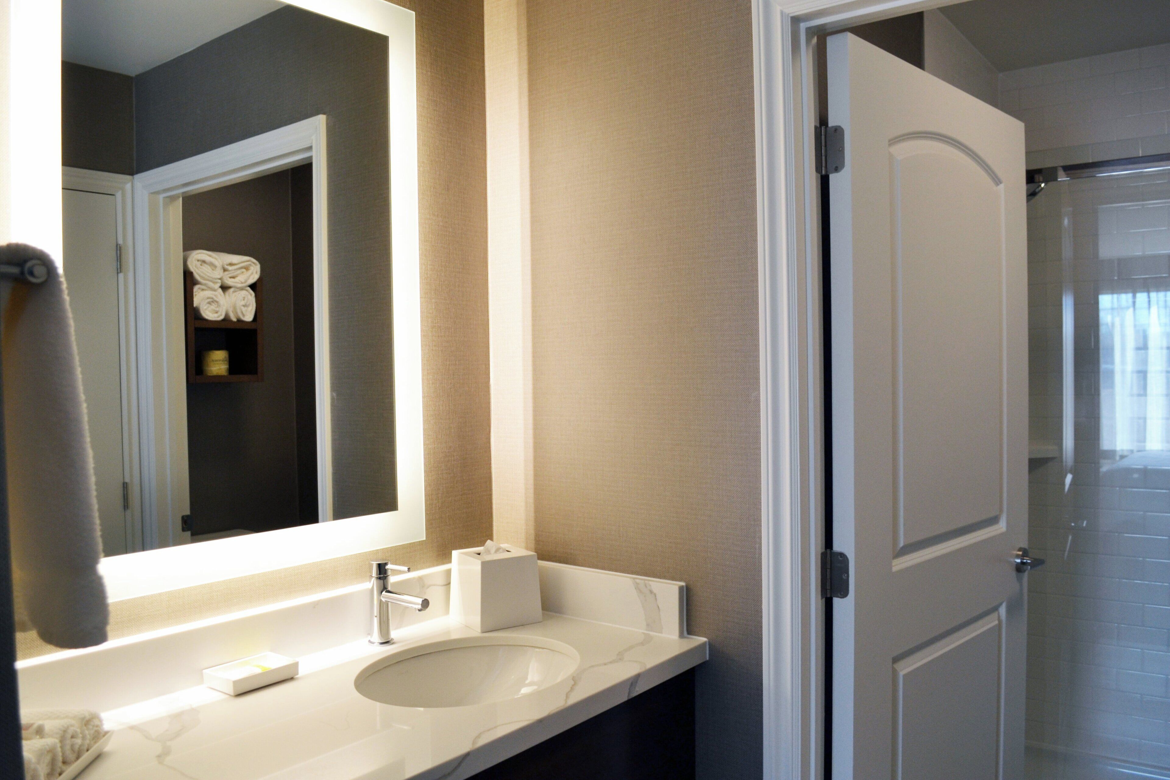 A bathroom with a white sink, a mirror, and a towel rack.