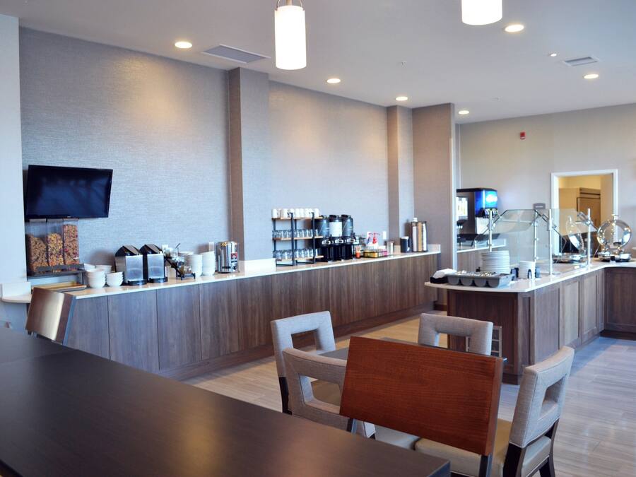 A modern hotel lobby with a reception desk, seating area, and a coffee station.