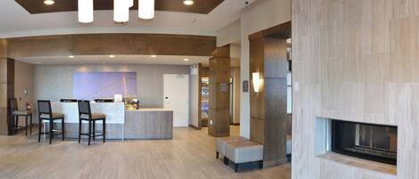A modern lobby with a reception desk, seating area, and a fireplace.