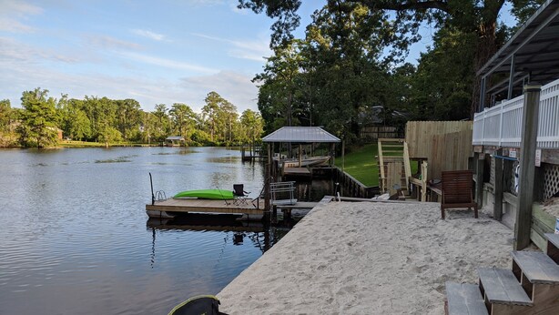 A lakeside dock with a boat, a covered seating area, and a sandy beach. - The Grey Goose (Waterfront) Historic New Bern - Private Beach - BRING YOUR BOAT! (New Bern)