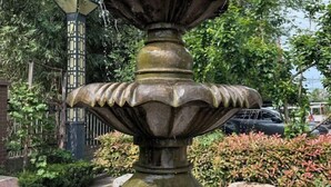 A stone fountain with a tiered design, surrounded by greenery and a fence. - Jinjiang Inn (Linzhou Hongqiqu Avenue Municipal Government) (Linzhou)