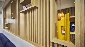 Una pared de madera con listones verticales, un rincón con asientos azules y un diseño geométrico amarillo.