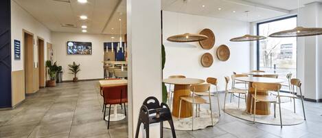 A modern interior with a dining area, a reception desk, and a large window.