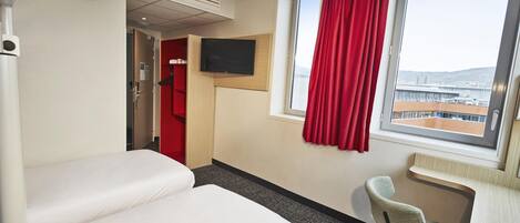 A hotel room with a bed, a desk, a chair, a TV, and a window with a view.
