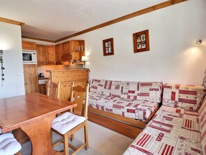 Una cocina compacta con armarios de madera, microondas y una mesa de comedor con sillas.