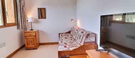 A cozy room with a wooden bed, a small wooden dresser, and a window with curtains.