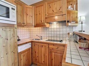 Una cocina con armarios de madera, microondas, lavamanos y salpicadero de azulejos.