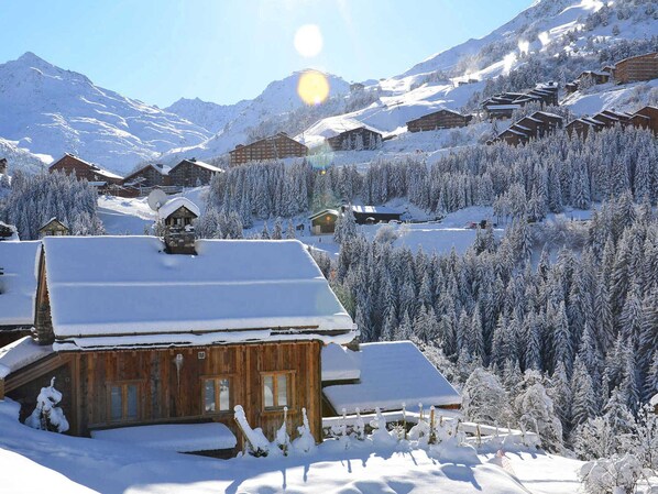 A snow-covered mountain village with wooden cabins and a ski resort in the background. - Charming 2-Room Apartment for 4 - Comfort and Wi-Fi (Méribel)