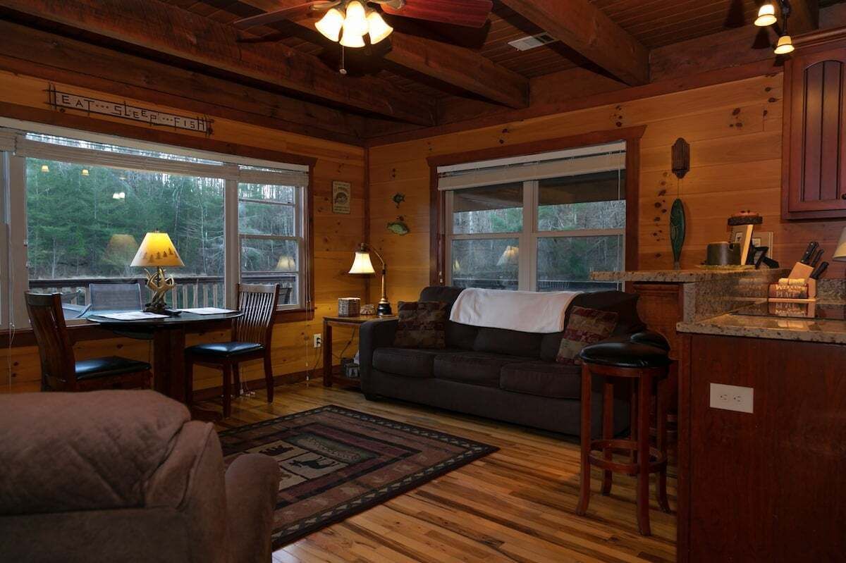 Un intérieur de chalet chaleureux avec une table à manger, des chaises, un canapé et un coin cuisine.