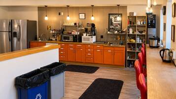 A modern kitchen with stainless steel appliances, wooden cabinets, and a bar area with red chairs.