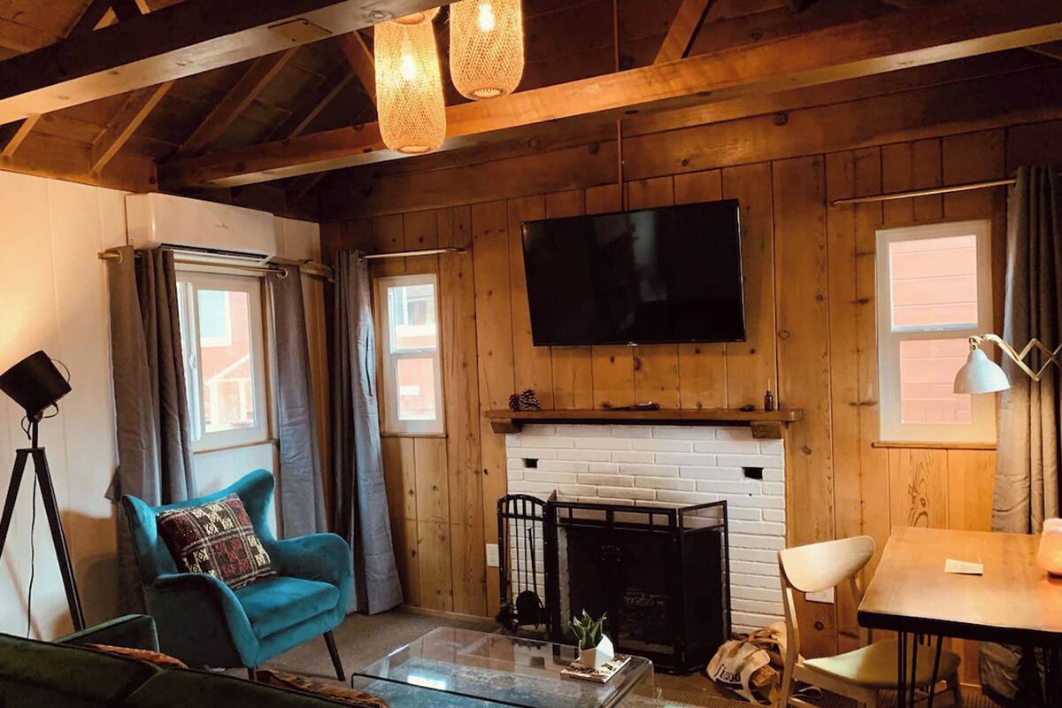 A cozy living room with a fireplace, a flat-screen TV mounted above it, and a comfortable seating area with a sofa and armchairs.