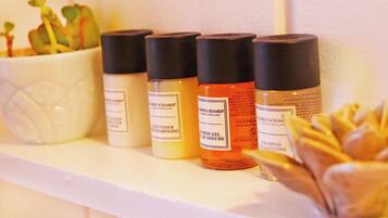 A shelf with four bottles of hair care products, a potted plant, and a decorative item.