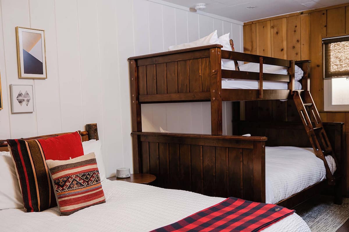 A bunk bed with a ladder, a bedside table, and a pillow with a patterned cover.