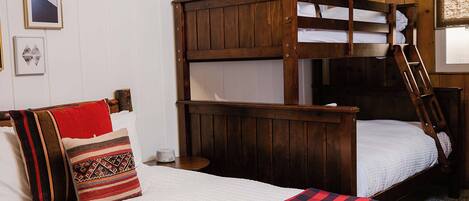 A bunk bed with a ladder, a bedside table, and a pillow with a patterned cover.
