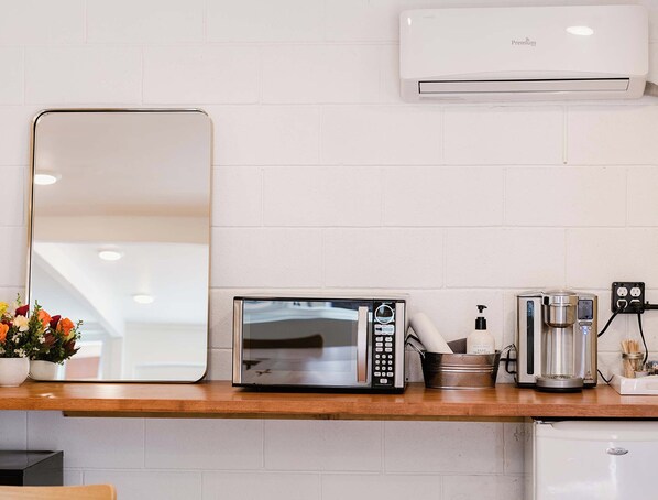 A kitchen with a microwave, coffee maker, and a wall-mounted air conditioner. - Grand Pine Cabins (Wrightwood)