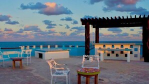 Eine Terrasse direkt am Strand mit Sitzgelegenheiten im Freien, einer Pergola und Meerblick.
