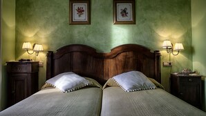 Uma cama de casal com cabeceira de madeira, duas mesas de cabeceira com luminárias e dois quadros florais emoldurados na parede.
