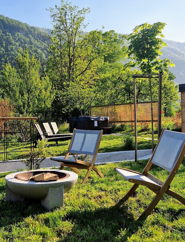A patio with two lounge chairs, a fire pit, and a pergola.