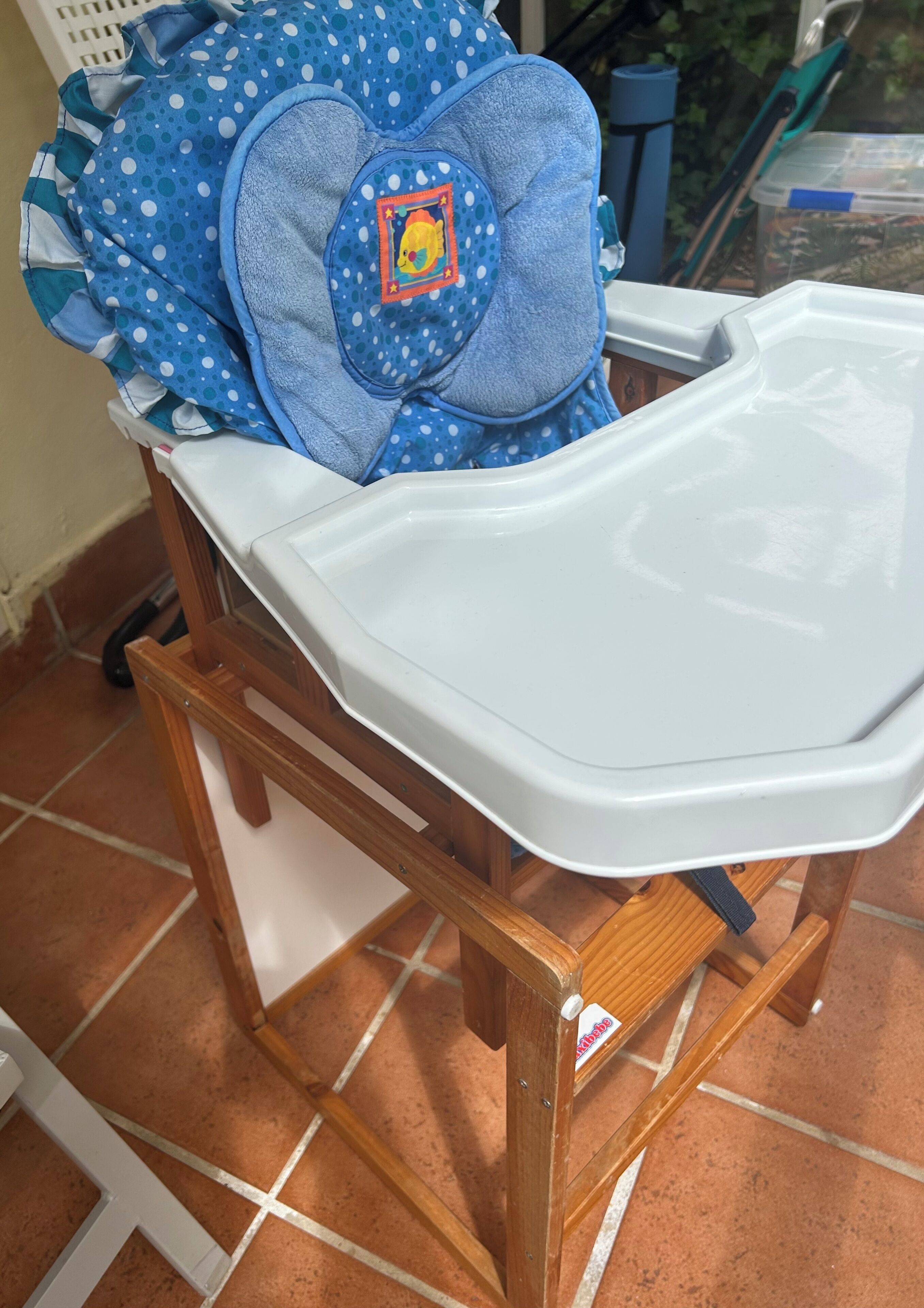 A baby changing station with a blue polka dot cover, a white tray, and a wooden frame.