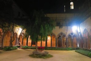 An indoor courtyard with arches, a central fountain, and a statue.