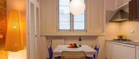 Una cocina con una mesa de comedor, sillas, una lámpara colgante y una ventana.