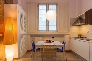 A kitchen with a dining table, chairs, a hanging light, and a window.