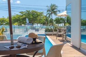 Ein Poolbereich mit Tisch, Stuhl, Sonnenhut und Handtuch.