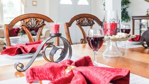 Een eettafel met een rode tafelkleed, een glas rode wijn, een kandelaar en een bord met eten.