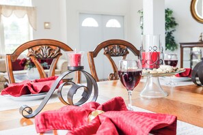 A dining table with a red cloth, a glass of red wine, a candle holder, and a plate with food.