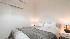 Ein Schlafzimmer mit einem Bett, Nachttischen, einer Lampe und einer Klimaanlage.