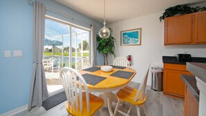 Un espace repas comprenant une table, des chaises et donnant sur l’extérieur.