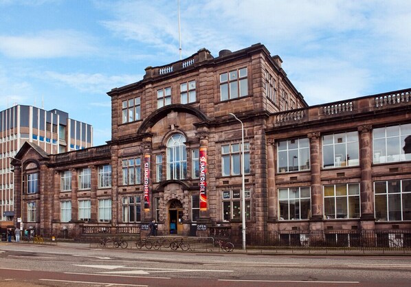 A historic building with multiple windows, a central entrance, and banners indicating a shop and a restaurant.