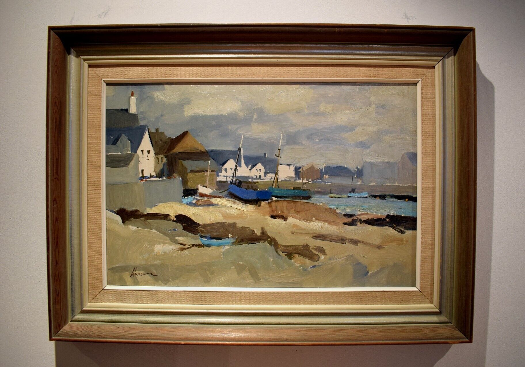 A framed painting of a coastal scene with buildings and boats.
