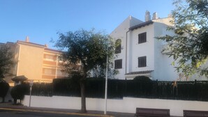 A street view with a white building, a bench, and a tree.